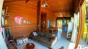 A spacious living area with a wooden ceiling, a sofa, a coffee table, and a colorful wall mural. - Casa Vista Privilegiada - Piscina e Mar (Garopaba)