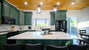 A kitchen with green cabinets, a large island, and pendant lights. - New, Modern, Bunk Room, Game Room, Playground, Hot tub (Broken Bow)