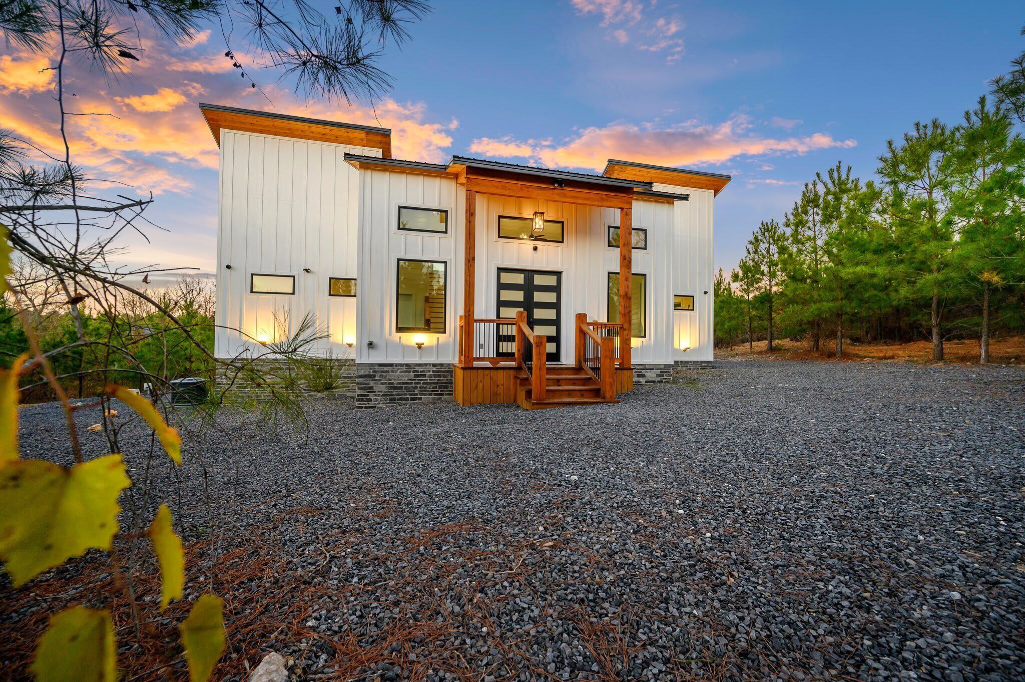 A modern two-story building with a wooden deck and a gravel driveway.