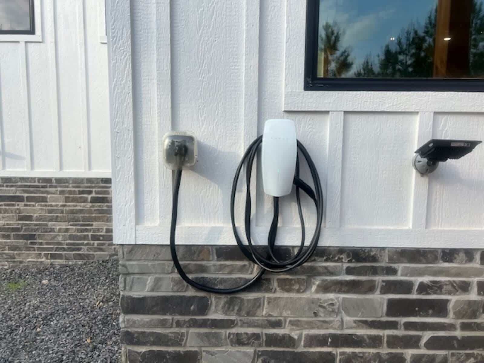 En laddstation för elfordon som är monterad på en tegelvägg intill ett fönster.