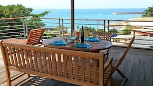 Terraza de madera con mesa lista para comer, con vista al mar.