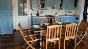 Una cocina con armarios azules, una mesa de comedor con sillas y una ventana con vistas.