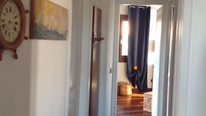 Un pasillo con suelo de madera, un reloj y un cuadro en la pared.