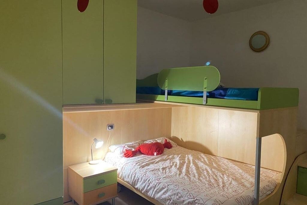 Un dormitorio con una cama nido, un escritorio con lámpara y una mesita de noche pequeña.