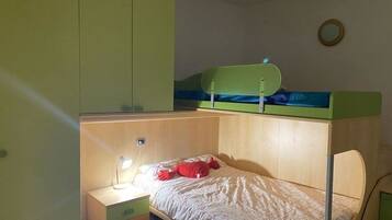 Un dormitorio con una cama nido, un escritorio con lámpara y una mesita de noche pequeña.