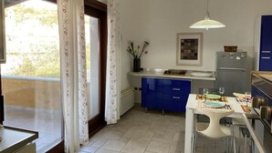 Una cocina compacta con armarios azules, una encimera blanca y una lámpara colgante.