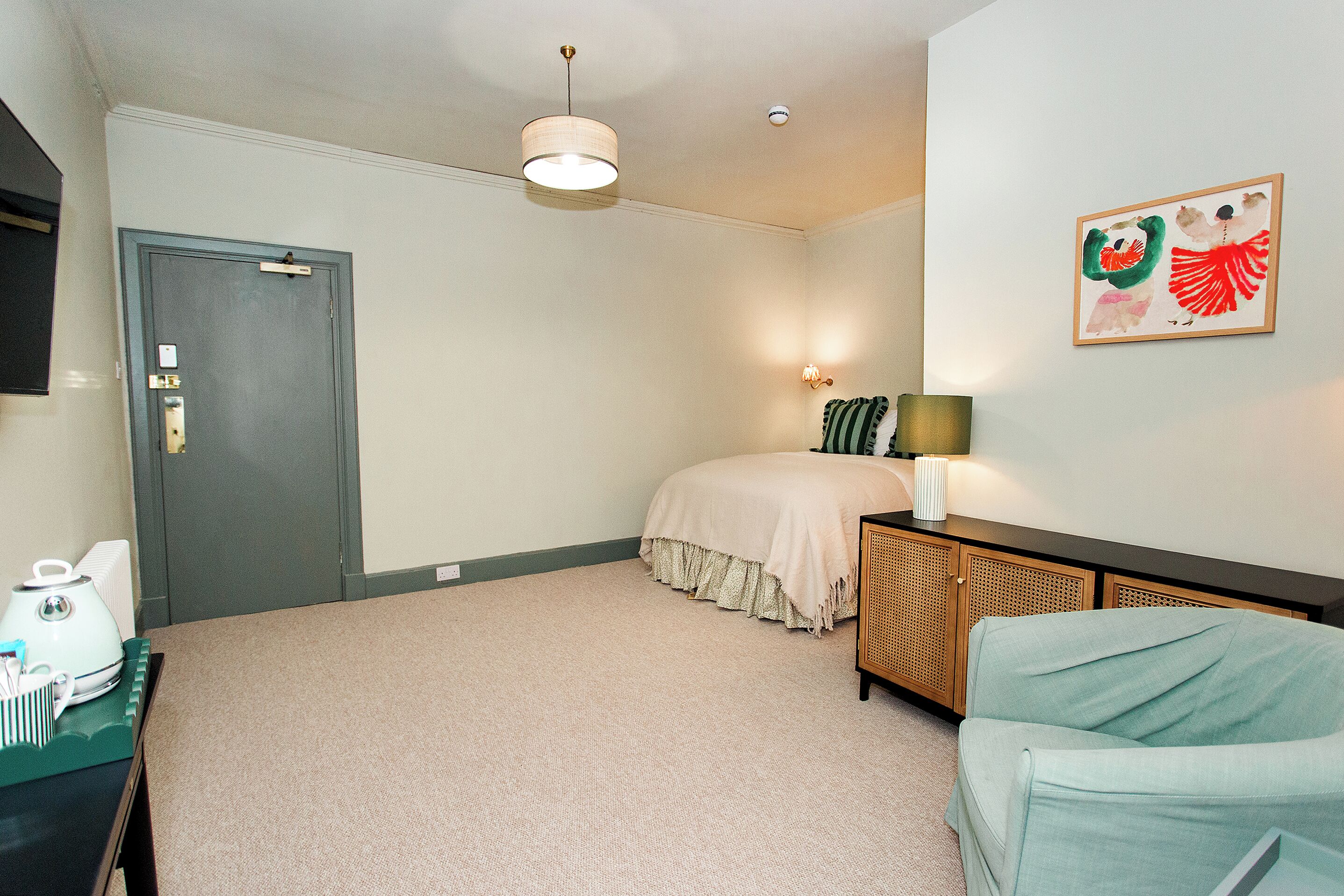 Une chambre à coucher comprenant un lit, un bureau, une chaise, une porte et une œuvre d’art accrochée au mur.