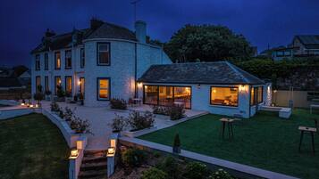 A two-story house with a well-maintained lawn and outdoor seating area.