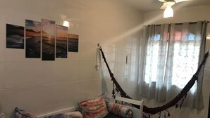 A room with a bed, a hammock, and a wall with four paintings. - MARESIAS BEACH - SP (Praia de Maresias São Sebastião)