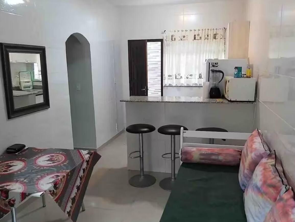 A compact kitchen with a refrigerator, a coffee maker, and a bar stool area.