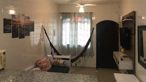 A compact living space with a hammock, a television, and a kitchenette. - MARESIAS BEACH - SP (Praia de Maresias São Sebastião)