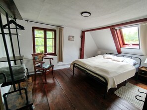 A bedroom with a bed, a chair, a radiator, and a window.