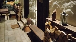 Un'area patio esterna con un rustico muro in pietra, panche in legno, un tavolino e un lampione.