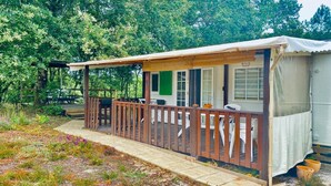A small, single-story cabin with a wooden deck and a covered porch.