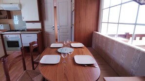 A compact kitchen with a dining area, wooden furniture, and a view through a window.