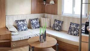 A cozy living area with a sofa, a round table with candles, and a window with blinds.