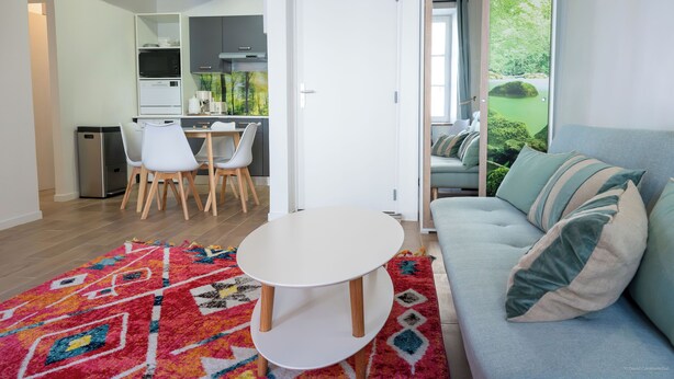 Ein modernes Wohnzimmer mit einer Couch, einem Couchtisch und Blick auf einen Garten durch eine Schiebetür.