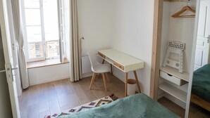 Ein kleiner, hell erleuchteter Raum mit Schreibtisch, Bett und Kleiderschrank.