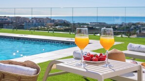 A poolside setting with two glasses of orange juice, a plate of strawberries, and a wicker basket. - Villa Leyni Torrox by Ruralidays (Málaga)