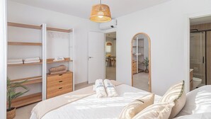 A modern bedroom with a bed, a wardrobe, a mirror, and a hanging light fixture. - Villa Leyni Torrox by Ruralidays (Málaga)