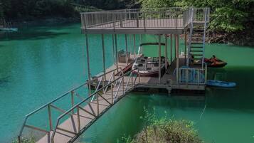 A wooden dock extending into a green lake with a boat and a Yamaha brand boat on it.