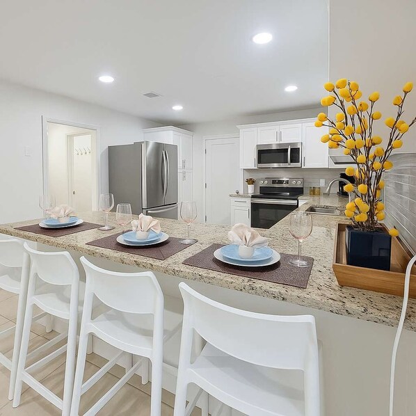 A modern kitchen with white cabinetry, stainless steel appliances, and a granite countertop.