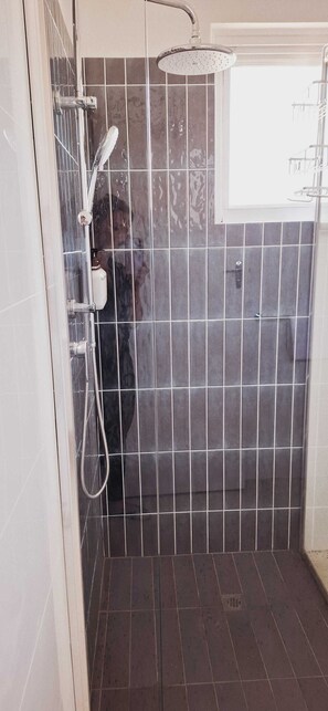 A shower area with a handheld showerhead and a wall-mounted showerhead. - Inviting Stay in Rockingham City Centre (Rockingham)