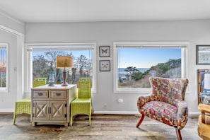 Enjoy the serene view from the large window, paired with a comfortable seating area featuring a wicker chair and armchair.