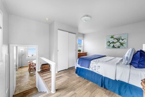 A bedroom with a bed, a painting, and a view of the outdoors. - Gog and Pop's Beach House - Ocean Views, WiFi, BBQ (Trinidad)