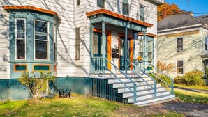 A two-story house with a porch and a set of stairs leading to the front door.