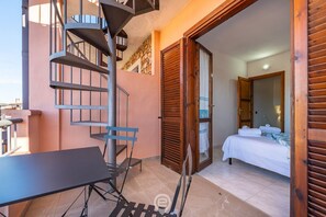 A bedroom with a bed, a wooden door, and a staircase leading to an outdoor area. - La perla nel blu - Villasimius (Villasimius)