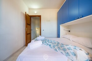 Een slaapkamer met een bed, een kledingkast en een deur naar een andere kamer.