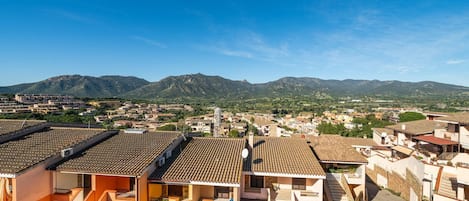 A residential area with terracotta-tiled roofs and a mountainous backdrop.