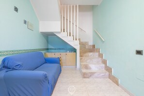 Una habitación con un sofá azul, una escalera y un armario con tapa estampada.