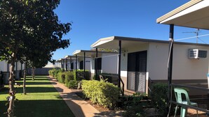 Una hilera de casas móviles con porches individuales, un césped cuidado y un cielo azul despejado.