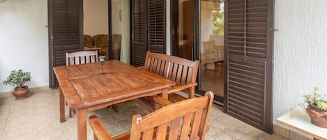 A wooden dining table with chairs, a potted plant, and a sliding glass door leading to another room.