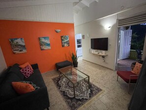 Una sala de estar con un sofá, una mesa de centro y un televisor montado en la pared.