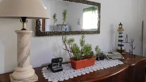A desk with a lamp, a mirror, a potted plant, a typewriter, and a small lighthouse model. - Wind Hostel (Valparaíso)