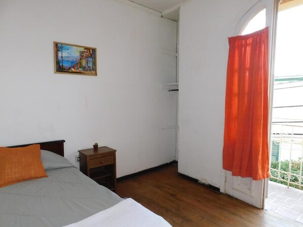 Una camera da letto con un letto, un comodino, un quadro e una finestra con tende.