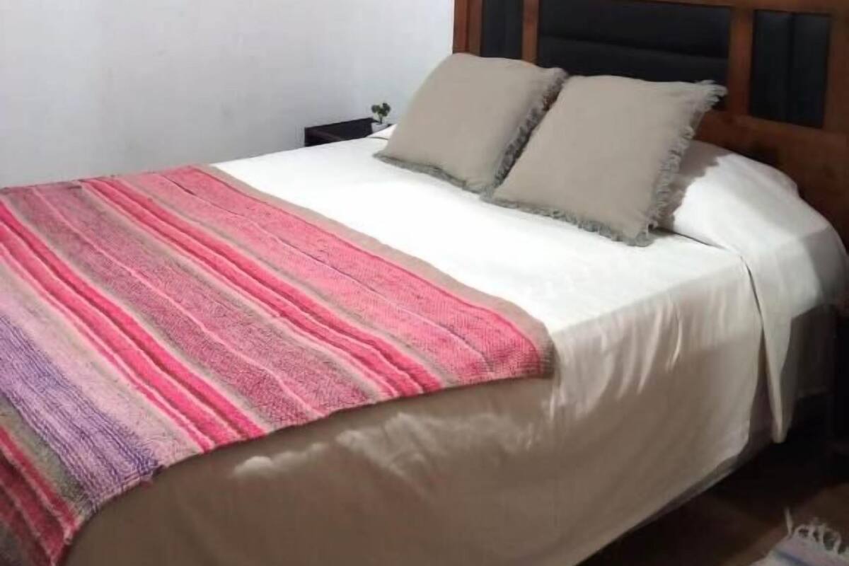 Una camera da letto con un letto, un comodino, un quadro e una finestra.