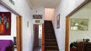 A staircase leading to a second floor, a purple sofa, a sewing machine, and a framed picture on the wall. - Wind Hostel (Valparaíso)
