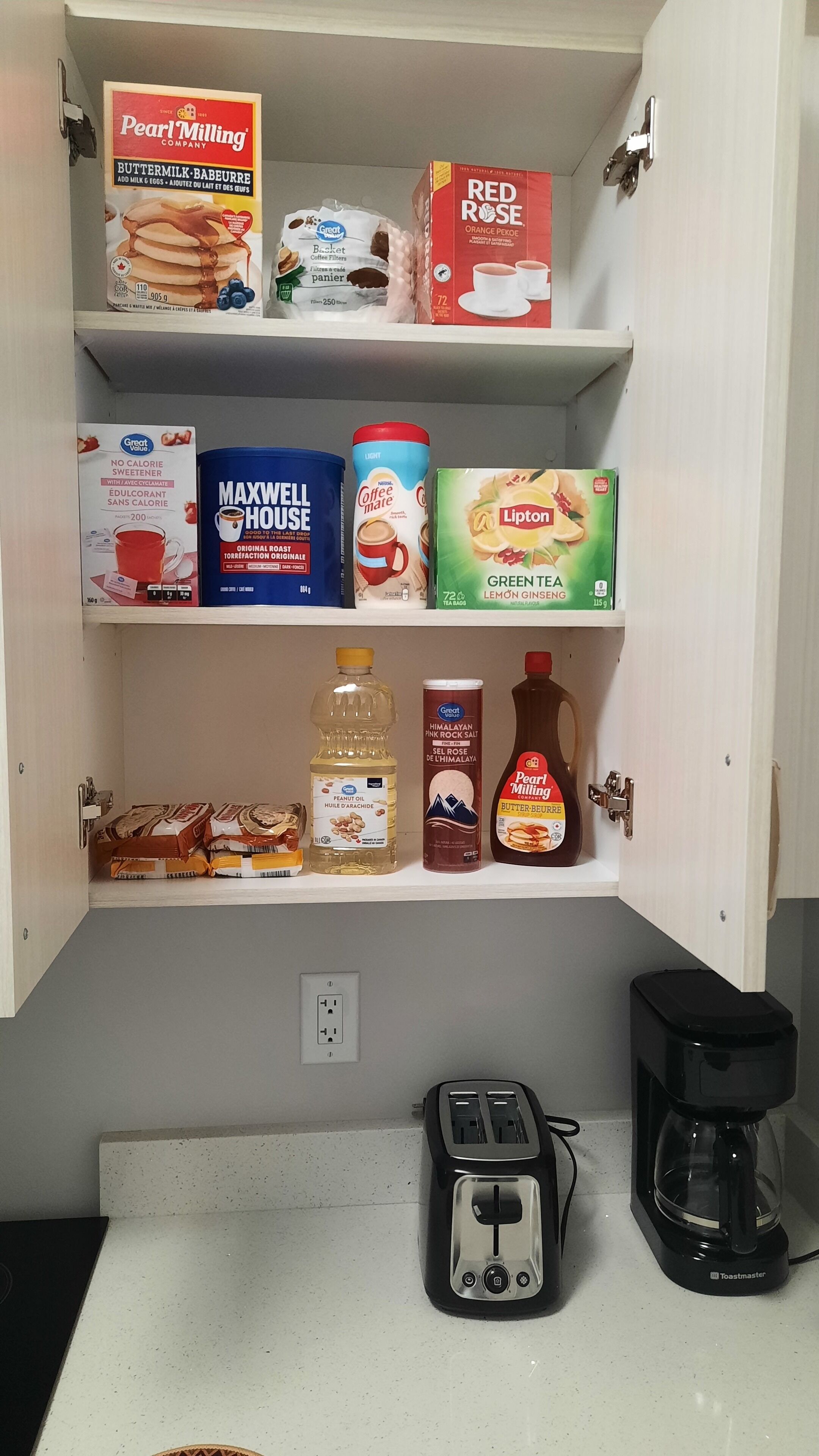 Een voorraadkast in de keuken met diverse etenswaren en keukenapparatuur.