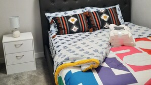 Un dormitorio con una cama, una mesita de noche y dos cuadros en la pared.