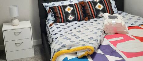 A bedroom with a bed, a nightstand, and two paintings on the wall.