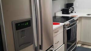 Una cocina moderna con electrodomésticos de acero inoxidable, incluyendo un refrigerador, microondas y horno.