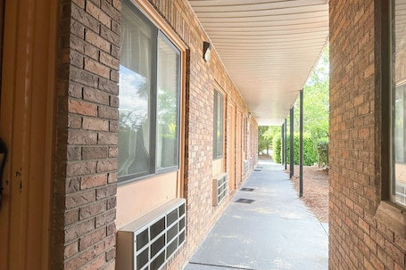 A covered corridor with brick walls and large windows.
