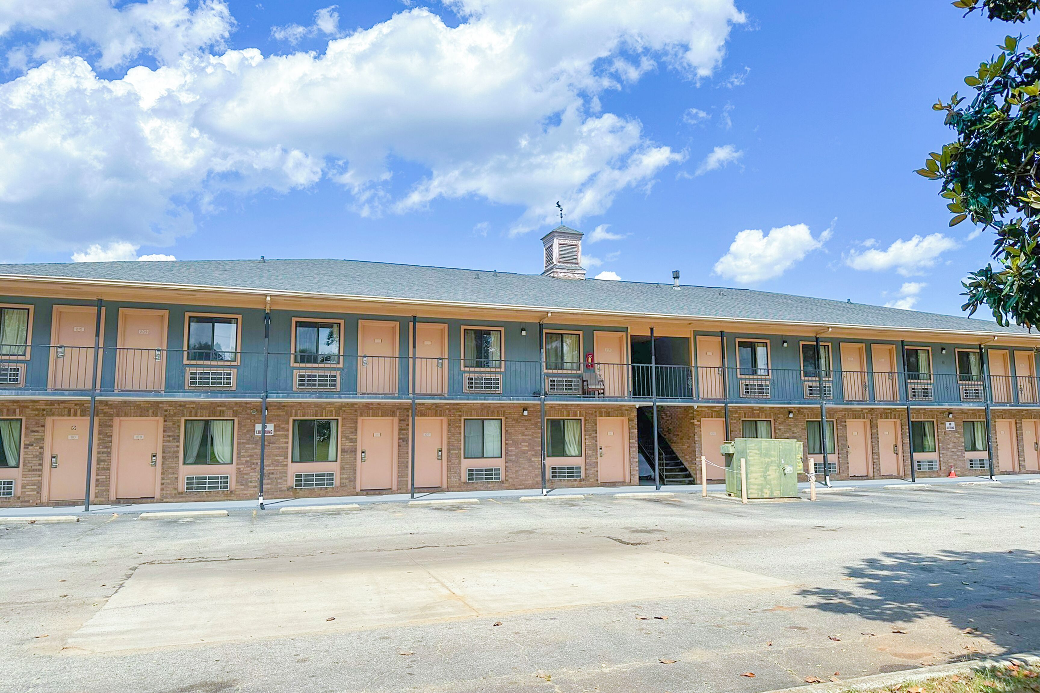 A multi-story motel with a flat roof, multiple balconies, and a central staircase.