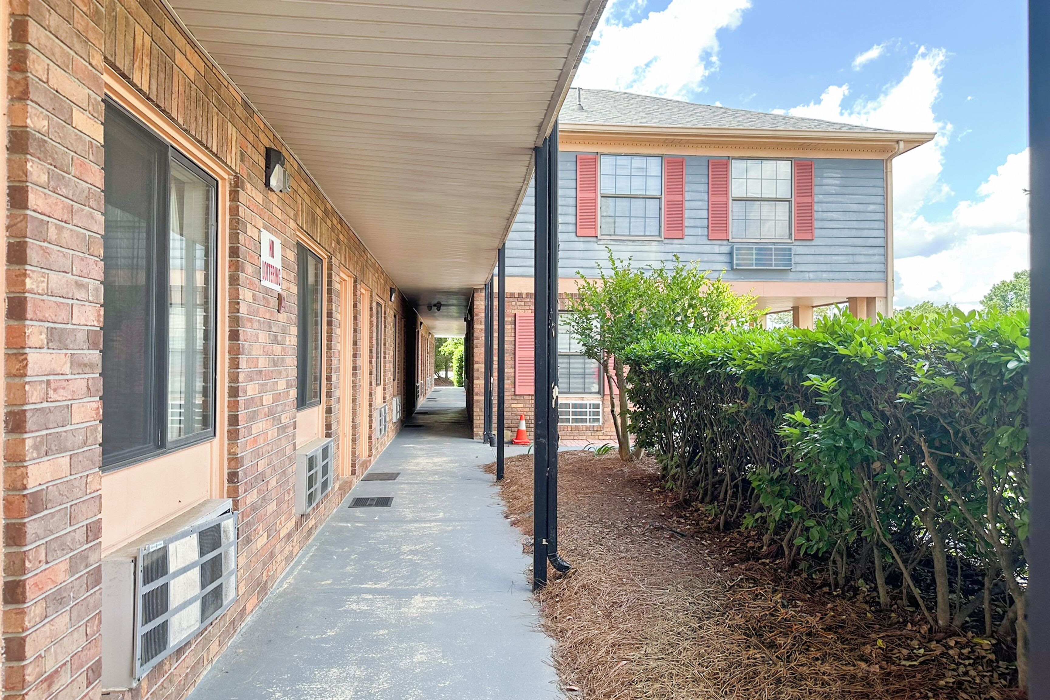 A covered walkway leading to a building with brick walls and large windows.