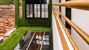 A balcony with a green artificial grass floor, a black window with white bars, and a white railing. - Park Lleras 11br Pool Jacuzzi (Medellín)