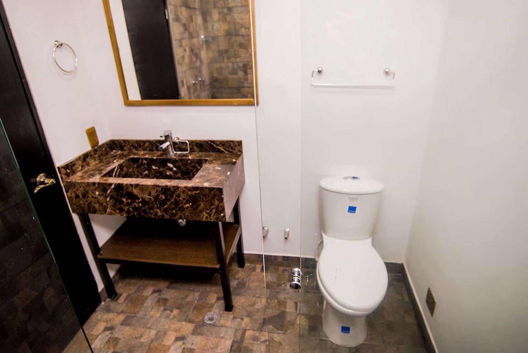 A bathroom with a marble sink, a white toilet, and a mirror above the sink.